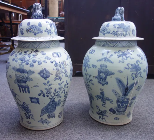 A pair of modern Chinese pottery vases and covers, each with Dog of Fo finial over a blue and white baluster form body, decorated with flora and fauna