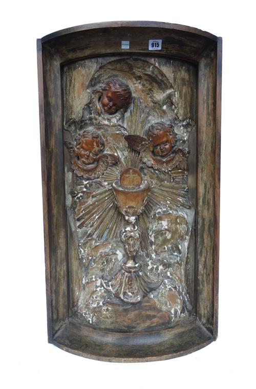 A South German relief carved wood and gesso convex panel, early 19th century, decorated with a central chalice emanating light surmounted by three ang