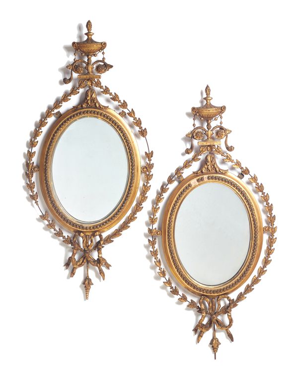 A pair of English oval gilt gesso wall mirrors, 19th century, with urn finials over an oval plate, with leaf border and bow finial (a.f), each 79cm hi