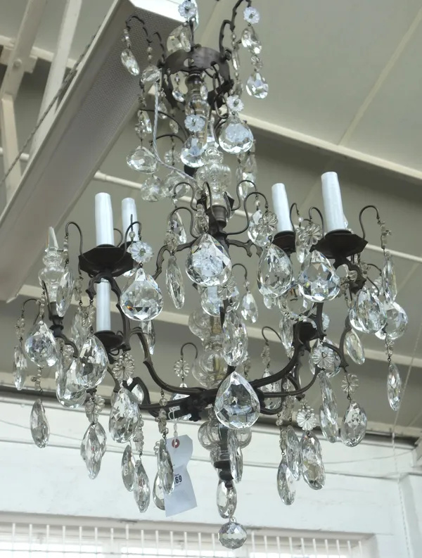 A patinated metal and glass eight light chandelier, 20th century, the glass baluster stem issuing twelve branches, over two graduated tiers hung with
