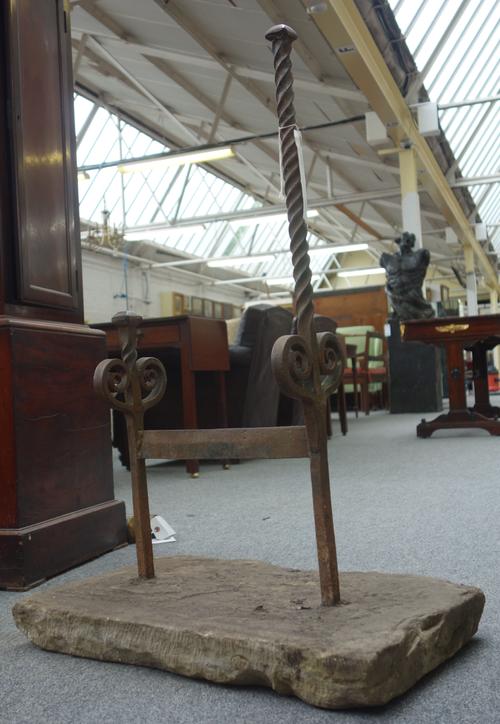 A Victorian style wrought iron boot scraper, with a barleytwist support and scroll finials, in a York stone rectangular base, 82cm high.