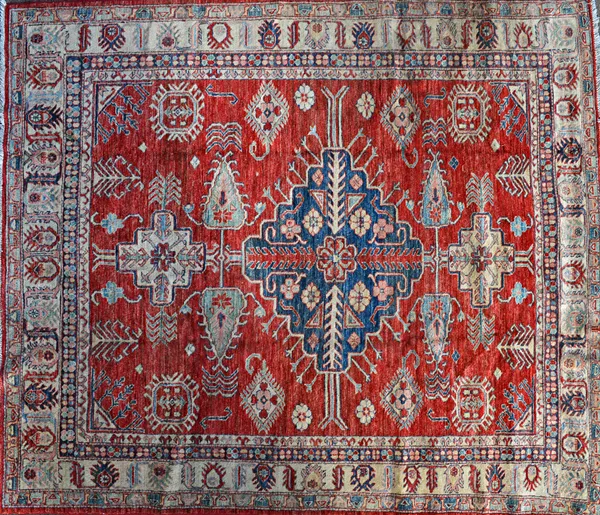 A North East Persian carpet, the madder field with a bold indigo medallion, bold motifs, a beige palmette and leaf border.  Illustrated