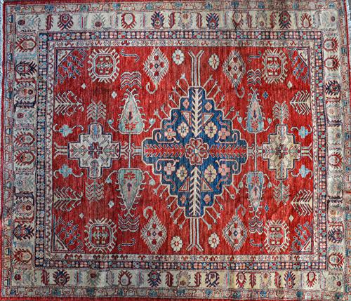 A North East Persian carpet, the madder field with a bold indigo medallion, bold motifs, a beige palmette and leaf border.  Illustrated