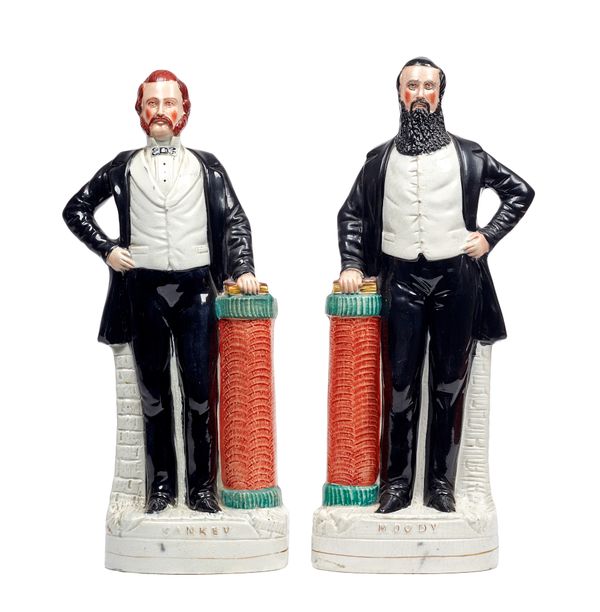A pair of Staffordshire portrait figures of Sankey and Moody, 19th century, polychrome painted, with one hand on a Bible atop a column at their side,