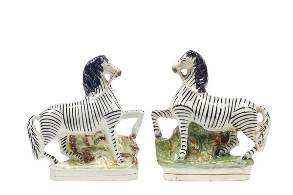 A pair of Staffordshire pottery flatback zebras, mid-19th century, polychrome decorated on a gilt lined oval base, 21cm high, (2).  Illustrated