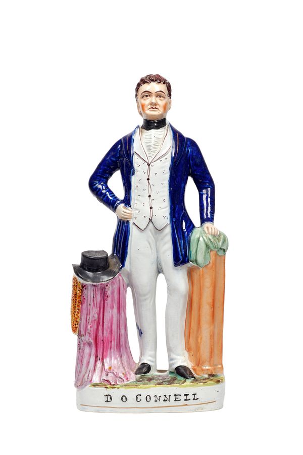 A Staffordshire portrait figure of Daniel O'Connell, 19th century, polychrome painted in a blue coat beside a draped pedestal, on a titled oval base,