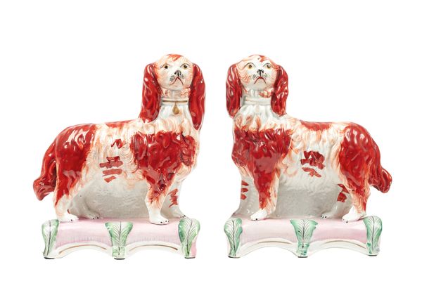 A pair of Staffordshire pottery spaniels, circa 1850, each dog modelled standing, with russet patches and gilt collars, atop pink shaped rectangular c