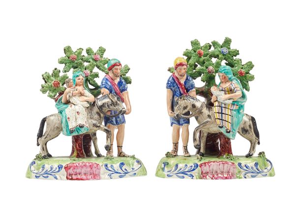 A pair of Staffordshire pearlware figure groups, circa 1820, both modelled with the Holy Family and Joseph leading a donkey, atop a naturalistic base,
