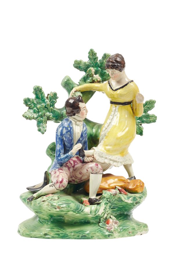 An unusual Staffordshire pearlware figure group, early 19th century, depicting a kneeling gentleman changing a lady's shoes, atop a naturalistic base,