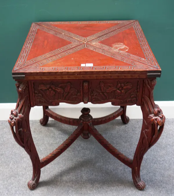 A late 19th century Art Nouveau red lacquered envelope card table, with floral carved frieze and supports, 77cm wide x 79cm high.