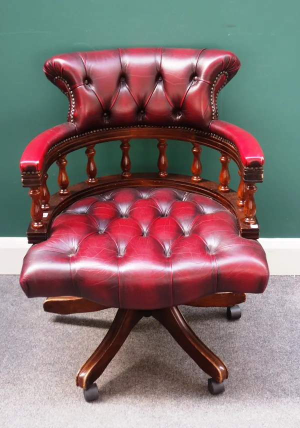A 20th century red leather upholstered tub back office swivel chair, with turned decoration, 63cm wide x 82cm high.