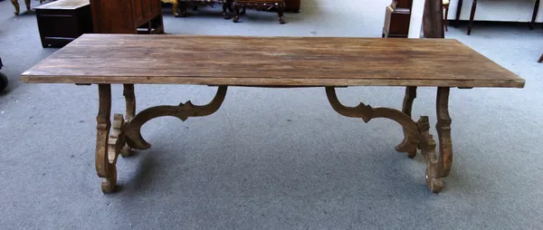 OKA; A bleached hardwood and pine Spanish style refectory table, on shaped supports and stretchers, 90cm wide x 250cm long.