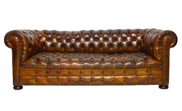 A 20th century Chesterfield sofa, with brass studded buttoned brown leather upholstery, on bun feet, 215cm wide x 75cm high.  Illustrated