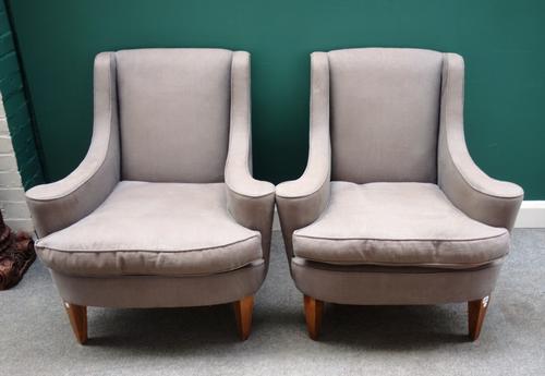A pair of 20th century grey upholstered easy chairs, with down and outswept arms, on tapering block supports, each 86cm wide x 91cm high, (2).