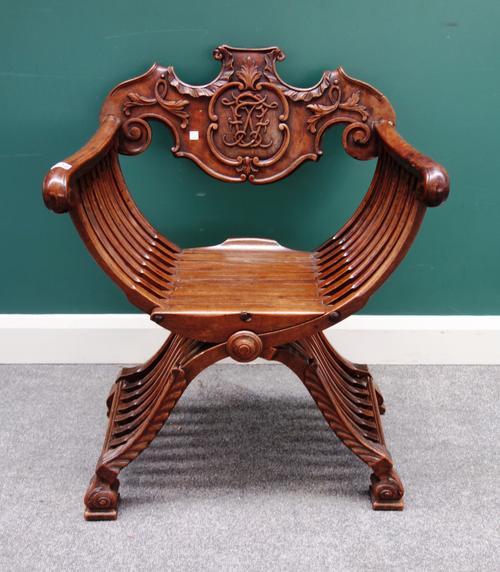 A 19th century French walnut folding X-frame chair, the carved back detailed with initials within a cartouche, 65cm wide x 84cm high.
