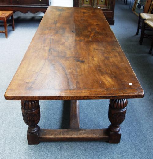 A 17th century style oak refectory table, on carved cup and cover supports united by H-frame stretcher, 86cm wide x 245cm long.