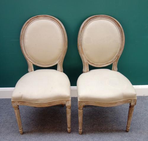 OKA; A set of eight Louis XVI style limed oak oval back dining chairs on tapering fluted supports, 51cm wide x 98cm high, (8).