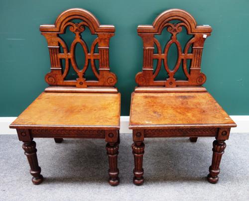 A pair of Victorian style burr oak hall chairs, 20th century, each with pierced open backs and solid seat on turned fluted supports, 56cm wide x 93cm