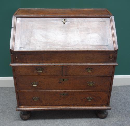 An early 18th century oak bureau, with stepped and welled interior over two short and two long drawers, on bun feet, 91cm wide x 99cm high.