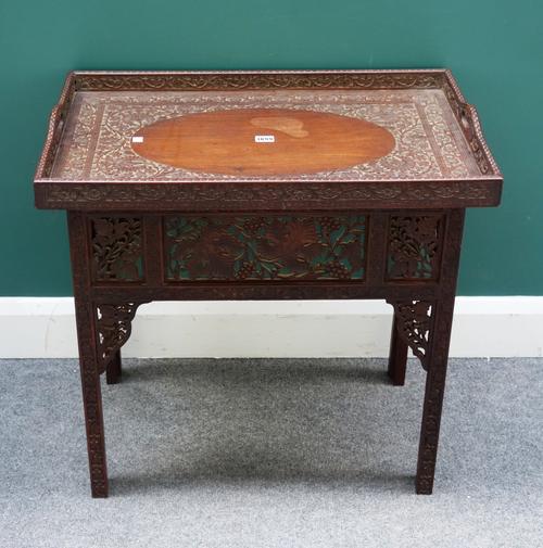 A late 19th century Indian rosewood tray table on folding base, relief carved and pierced with floral decoration, 71cm wide x 70cm high.