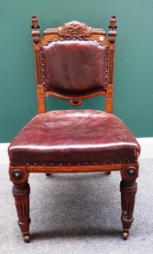 Lamb of Manchester; a set of fifteen Victorian carved oak dining chairs, with lion and shield finials and floral wreath tied crests, over shallow bow