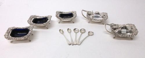 Silver, comprising; two similar mustard pots and three similar salts, each of curved rectangular form, having cast borders and raised on four lion mas