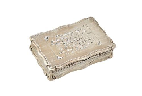 A Victorian silver hinge lidded snuff box, of shaped rectangular form, the cover presentation inscribed, otherwise engine turned, maker Edward Smith,