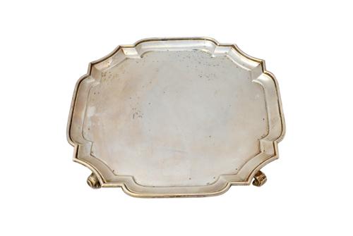 A silver salver of shaped square form, in the early 18th century taste, raised on four scrolling feet, diameter 25.5cm, London 1929, weight 635 gms.