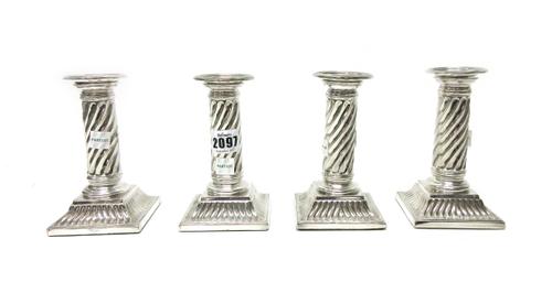 A set of four silver plated table candlesticks, each modelled as a spiral fluted column, on a stepped square base, the tops with detachable sconces, h