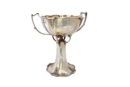 A silver twin handled trophy cup, the shaped body applied with foliate motifs, the bowl raised on scroll supports detailed Faraday House Cup and raise