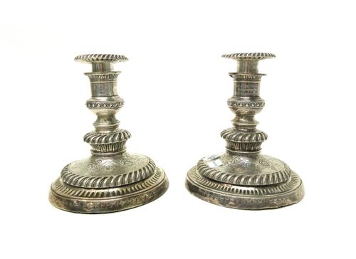 A pair of silver table candlesticks, each with scroll and floral embossed decoration within gadrooned rims, the tops presentation inscribed, with deta