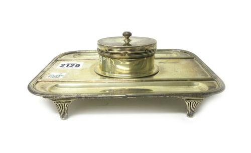 A silver curved rectangular single bottle inkstand, the centre with a hinged oval ink bottle compartment, a recessed pen tray to either side, within r