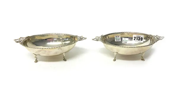 A pair of silver twin handled bonbon bowls, each of oval form, the handles formed as ribbon tied bows, each raised on four pad feet, by Walker & Hall,