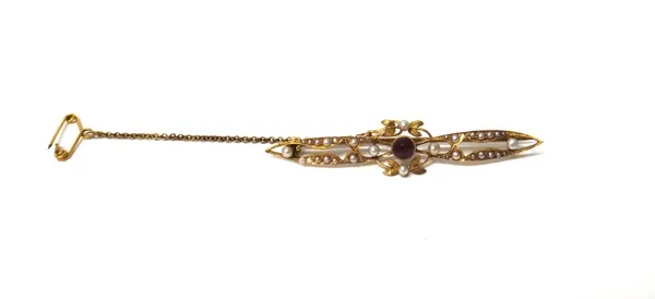 A gold, seed pearl and garnet set bar brooch, in a pierced openwork design, with foliate motifs, mounted with the cushion shaped garnet at the centre