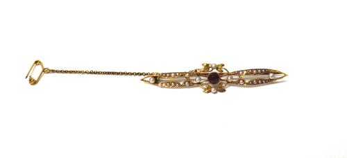 A gold, seed pearl and garnet set bar brooch, in a pierced openwork design, with foliate motifs, mounted with the cushion shaped garnet at the centre