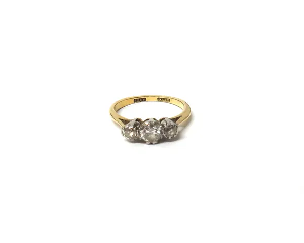 A gold and platinum, diamond set three stone ring, claw set with a row of circular cut diamonds and with the principal diamond mounted at the centre,