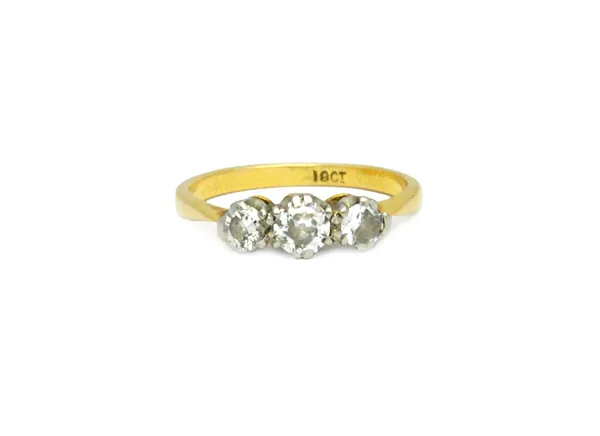 A gold and diamond set three stone ring, claw set with a row of cushion shaped diamonds and with the principle diamond mounted at the centre, detailed
