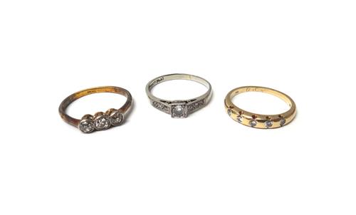 A gold and diamond set three stone ring, mounted with cushion shaped diamonds, a 9ct gold and diamond set five stone ring and a white gold and platinu