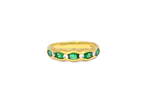 An 18ct gold, emerald and diamond ring, mounted with five oval cut emeralds alternating with four smaller circular cut diamonds, in a wavy design, det