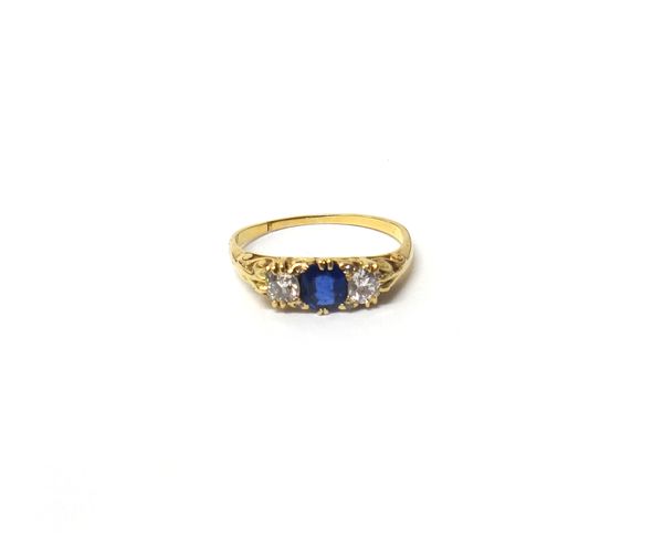 A gold, sapphire and diamond ring, claw set with the oval cut sapphire at the centre, between two cushion shaped diamonds and further set with diamond