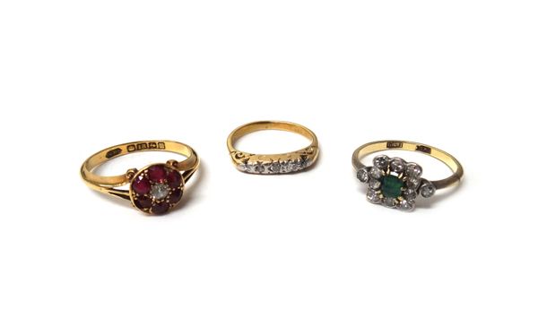 An 18ct gold, ruby and diamond set seven stone cluster ring, Birmingham 1911, a gold and platinum, emerald and diamond set rectangular cluster ring an