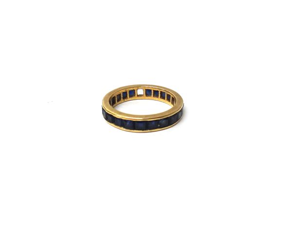 A gold and sapphire set full eternity ring, mounted with calibre cut sapphires (one sapphire lacking), ring size P and a half, gross weight 4.6 gms.