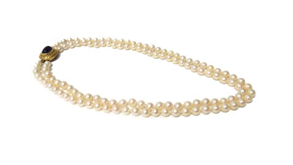 A two row necklace of uniform cultured pearls, on a gold and cabochon amethyst set oval clasp, decorated with bead and wirework to the border, in the