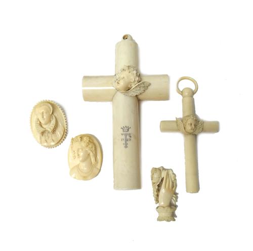 A group of 19th century ivory jewellery and works of art, comprising; one large and one smaller crucifix, each with a central carved winged cherub's f