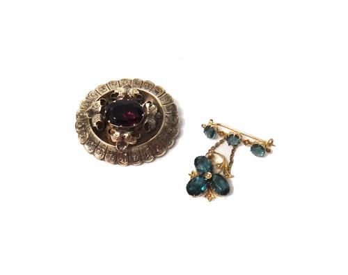 A Victorian shaped oval brooch, centred by an oval cut garnet, within a foliate surround, the back glazed with a locket compartment and a gold, seed p