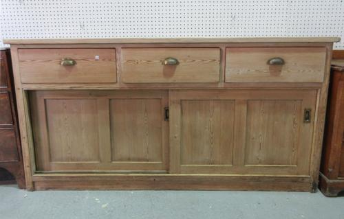 A large pine dresser base, with three drawers and a pair of sliding panel doors, 182cm wide x 91cm high.  D10