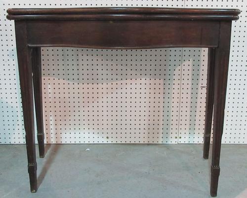 A George III mahogany card table, with serpentine fold-over top on channelled tapering supports, 91cm wide.   E4