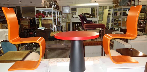 A 20th century red and ebonised child's circular table, 70cm wide, together with a pair of 20th century design orange painted chairs, (3).   H6