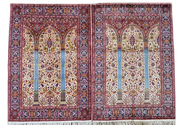 A pair of Indian part silk prayer rugs, the ivory flower filled mihrab with madder arch, indigo flower border, each 134cm x 130cm, (2).  Illustrated