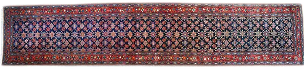 A West Persian runner, the dark indigo field with an all over mina hani design, a madder trailing flower and vine border, 536cm x 109cm.  Illustrated
